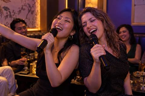 Friends singing together in an elegant, gold-framed karaoke lounge
